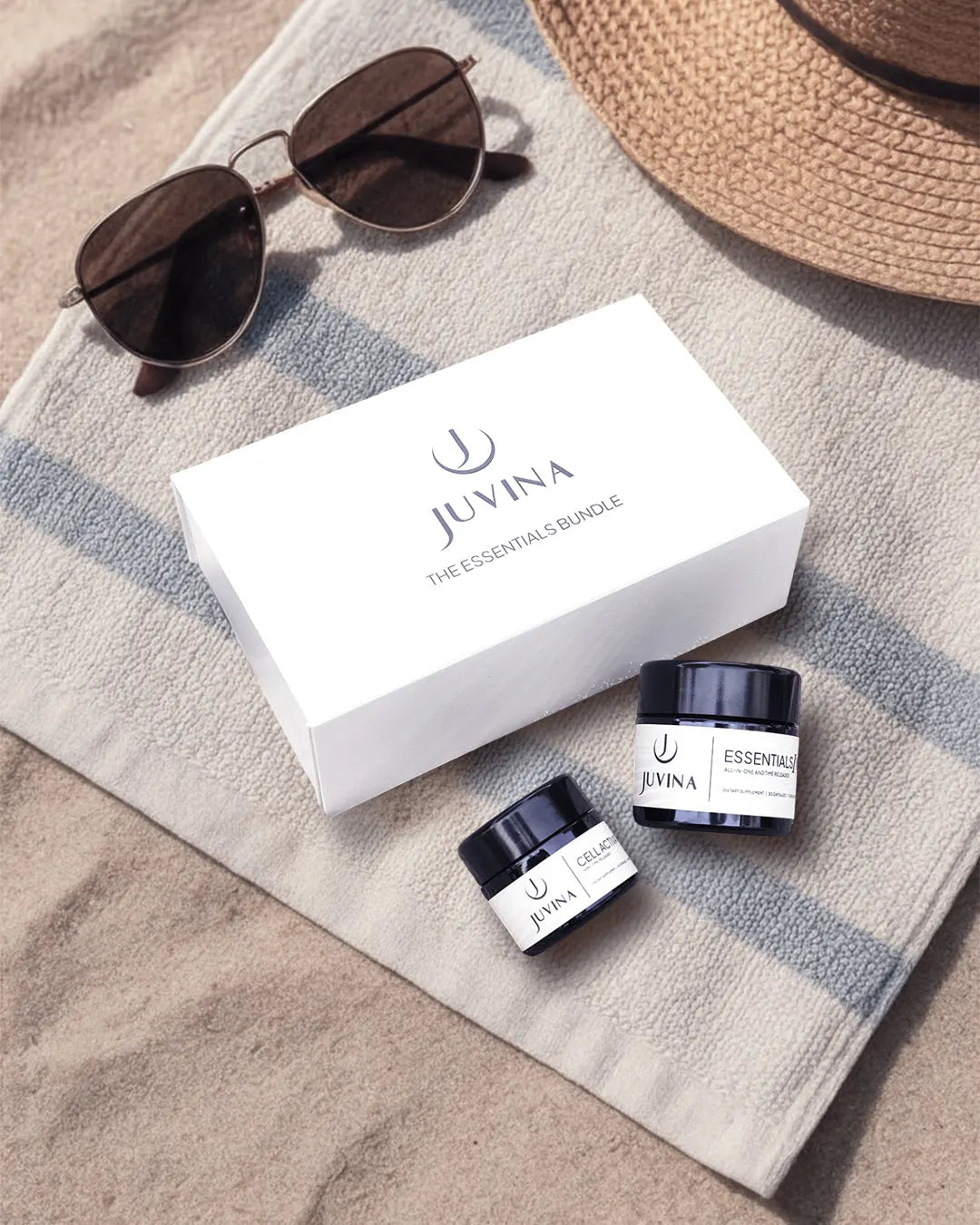 Juvina Bioscience The Essentials Bundle featuring Cell Activator XR and Essentials I XR supplement jars on a beach towel flatlay.